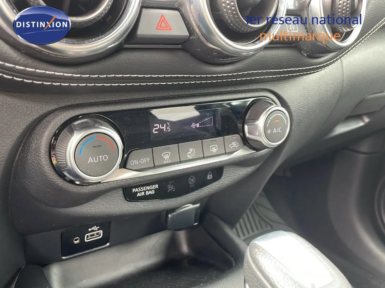 Détail de la console centrale du Nissan Juke Hybrid 2023 avec commandes climatisation et port USB, finition cuir gris.