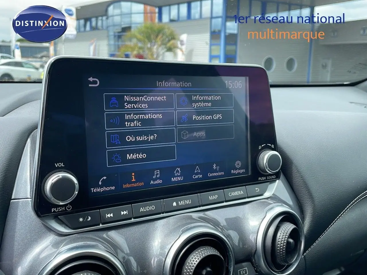 Écran tactile central du Nissan Juke Hybrid 2023 affichant menu d'informations, entouré de commandes et aérateurs gris perle métallisé.