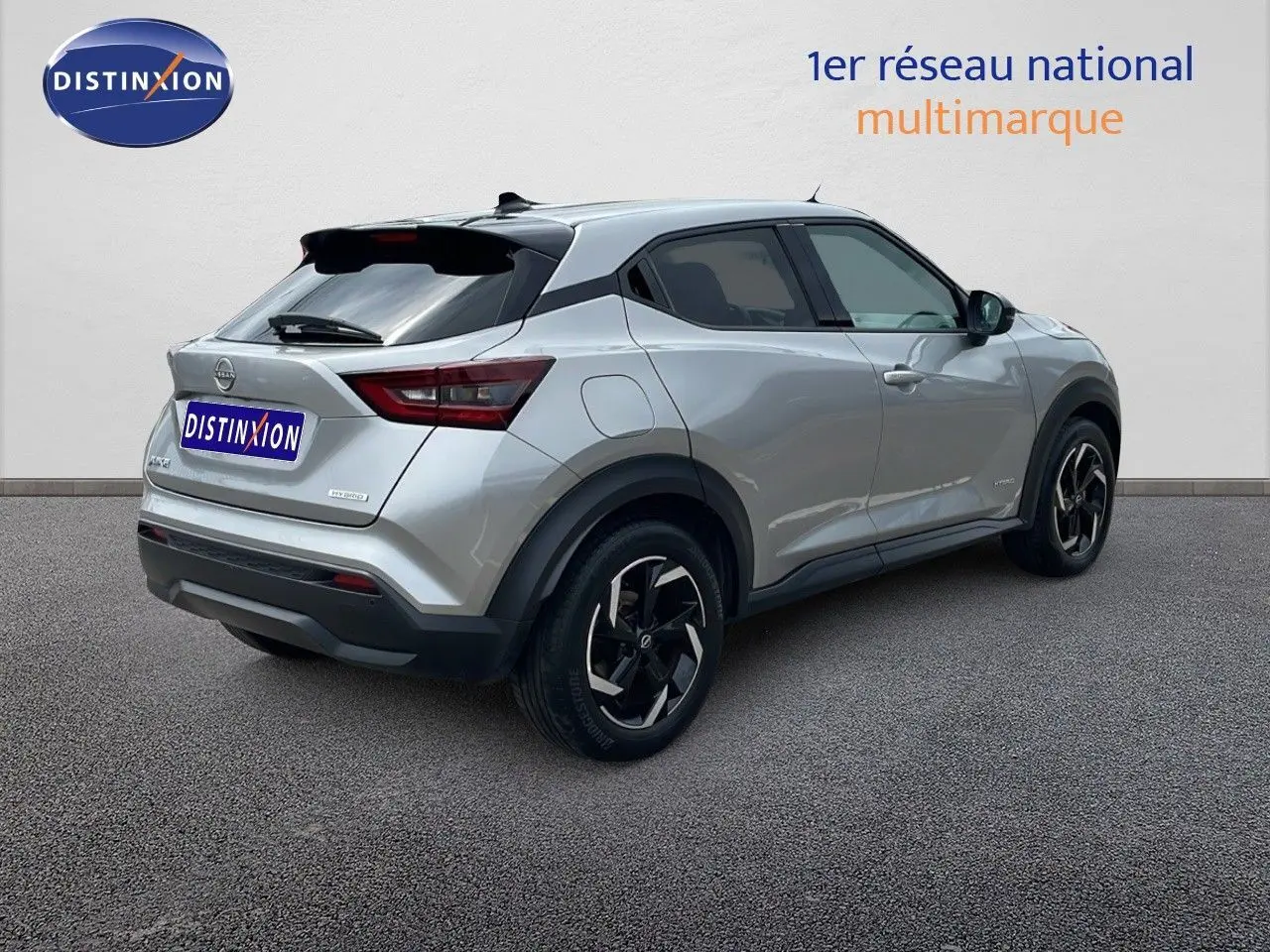 Nissan Juke Hybrid gris perle métal vu en 3/4 arrière droit, avec jantes noires et toit noir contrasté.