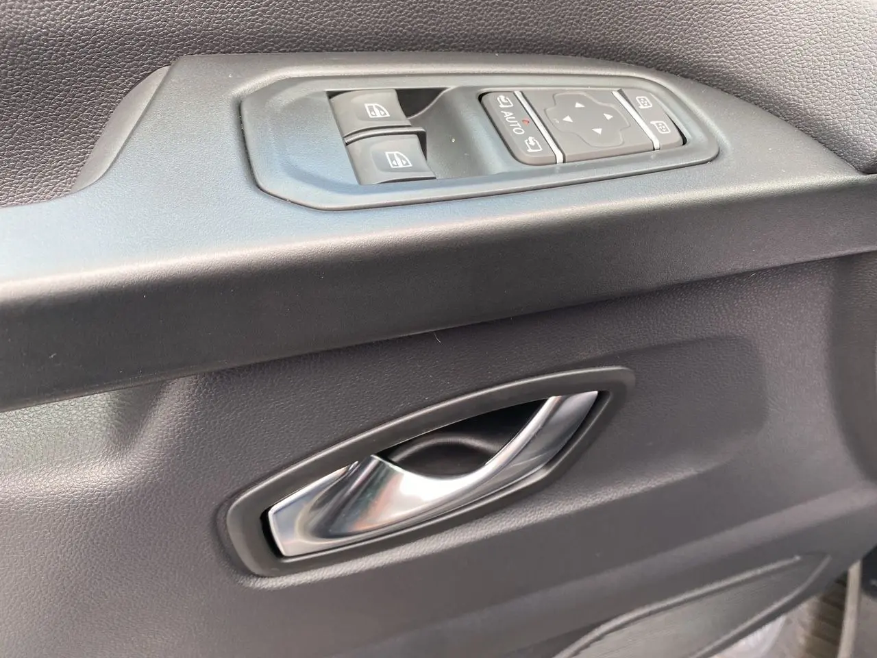Poignée de porte intérieure grise avec commandes électriques des vitres et rétroviseurs du Renault Trafic cabine approfondie.