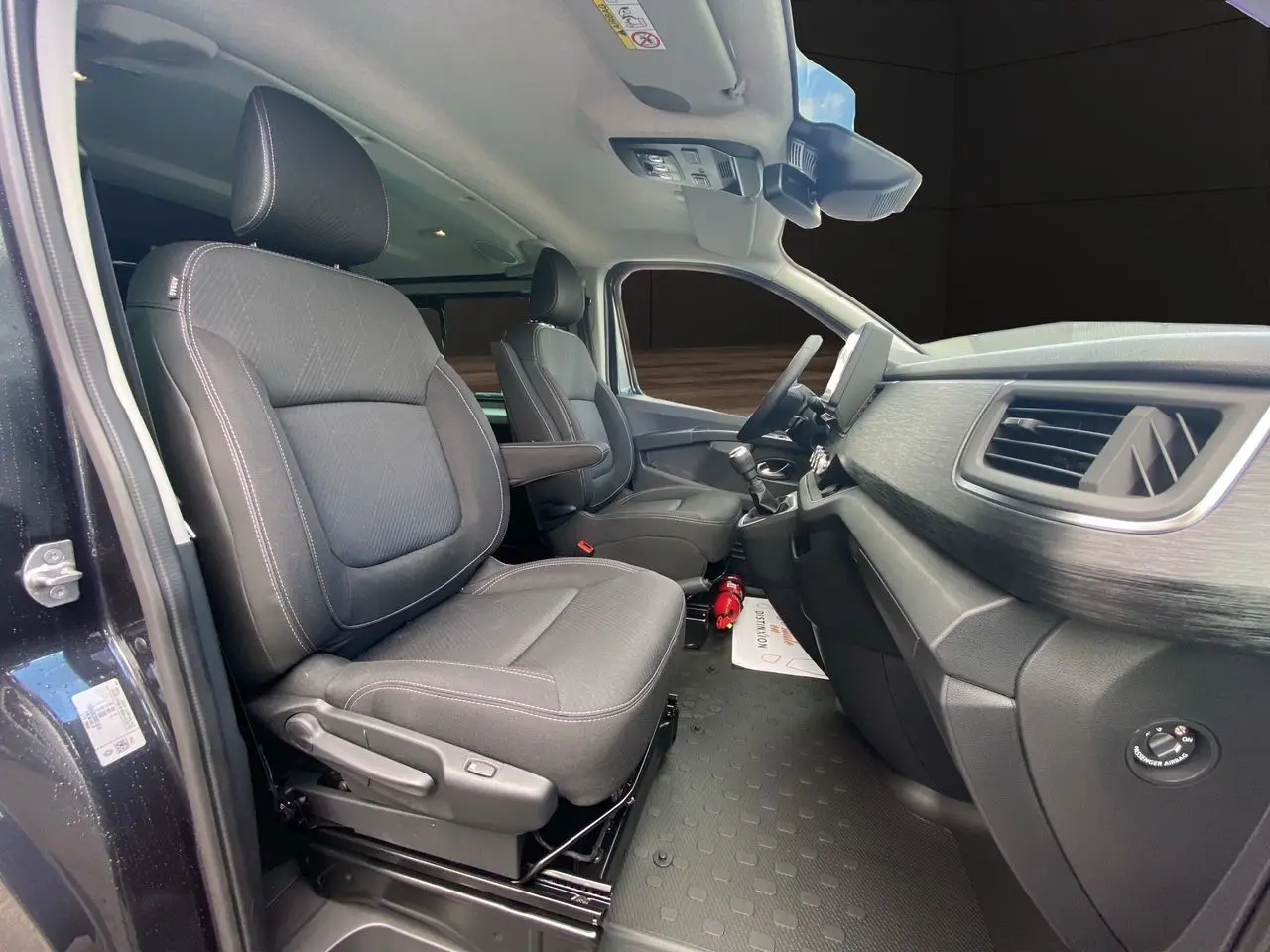 Intérieur avant du Renault Trafic gris comète, sièges noirs avec accoudoirs et tableau de bord moderne vu côté conducteur.