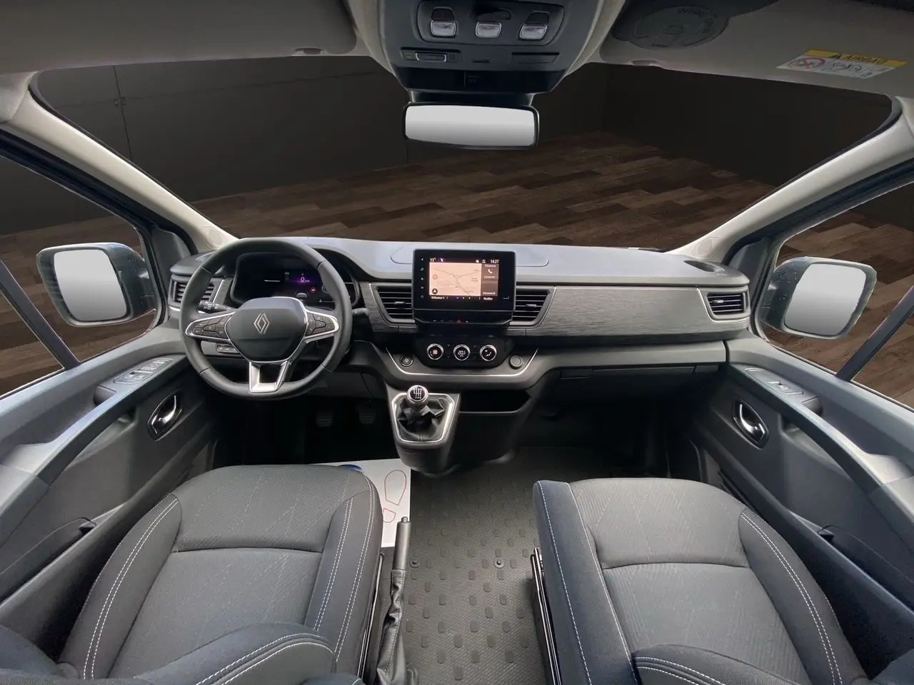 Vue intérieure avant du Renault Trafic cabine approfondie 2025, tableau de bord moderne avec écran tactile et sièges noirs.