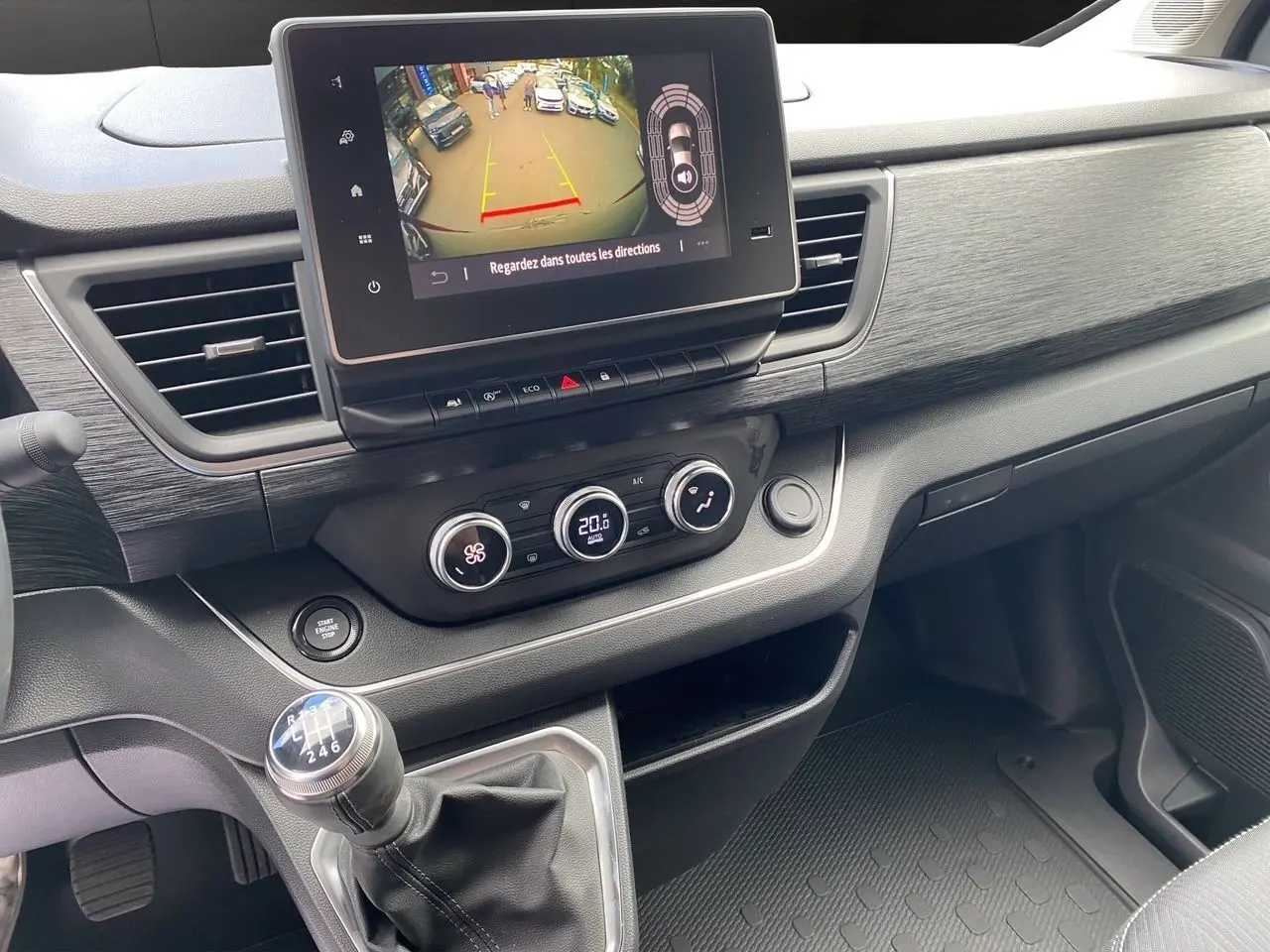 Vue intérieure du tableau de bord du Renault Trafic gris comète avec écran tactile et levier de vitesses manuel.