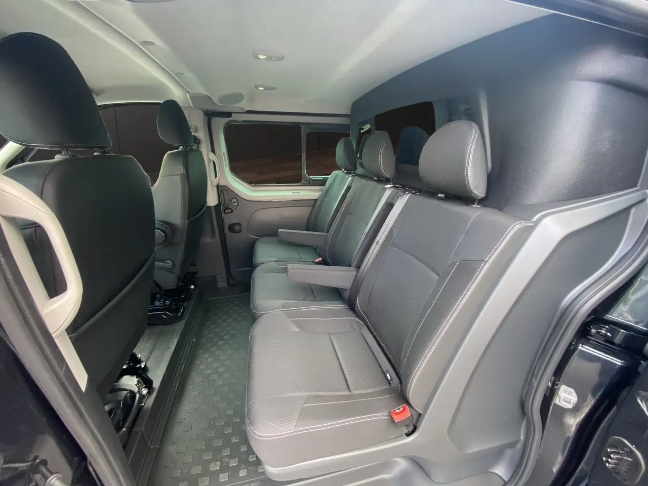 Vue intérieure côté droit des sièges arrière noirs du Renault Trafic Cabine Approfondie 2025 avec porte latérale ouverte.