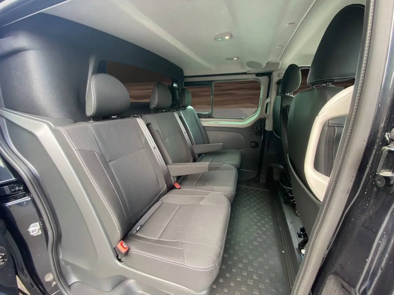 Vue intérieure côté droit des sièges arrière noirs du Renault Trafic Cabine Approfondie 2025 avec porte latérale ouverte.