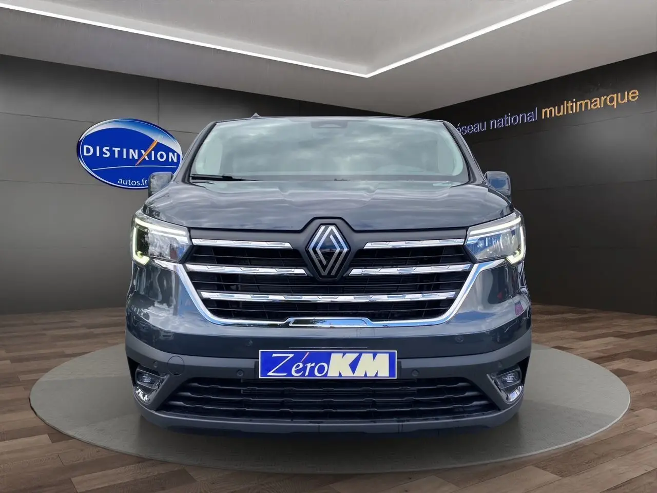 Vue frontale d'un Renault Trafic cabine approfondie gris comète avec calandre chromée et phares LED allumés.