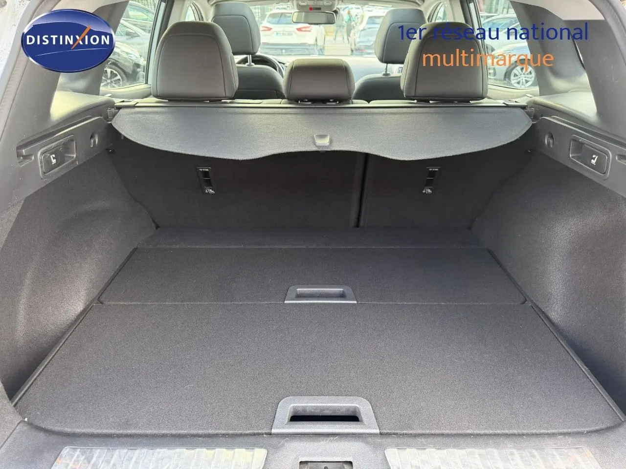 Vue intérieure du coffre spacieux d'un Renault Kadjar blanc nacré, avec banquette arrière et cache-bagages déployés.