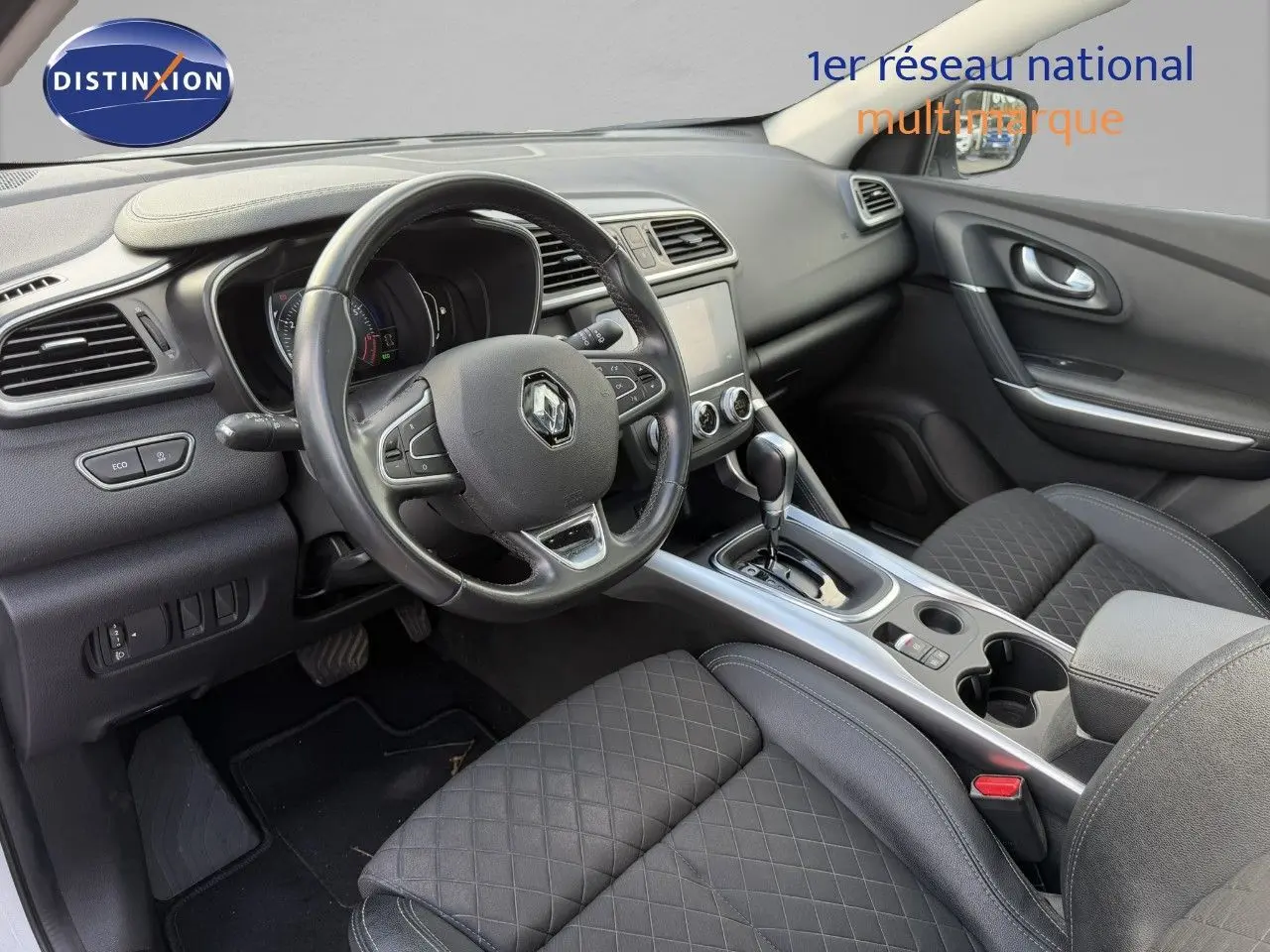 Intérieur du Renault Kadjar 2019, vue côté conducteur, volant cuir, console centrale avec boîte auto et sièges tissu noir matelassé.