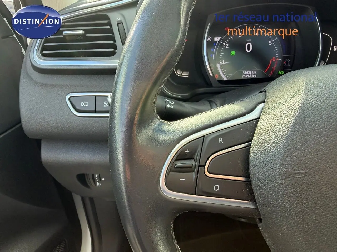 Gros plan sur le volant noir et le tableau de bord numérique du Renault Kadjar blanc nacré, avec boutons de commande visibles.