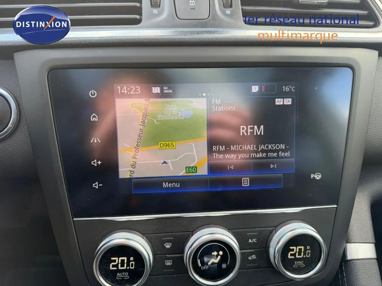 Vue rapprochée de l’écran tactile central et de la console de climatisation du Renault Kadjar blanc nacré, affichant la navigation et la radio.