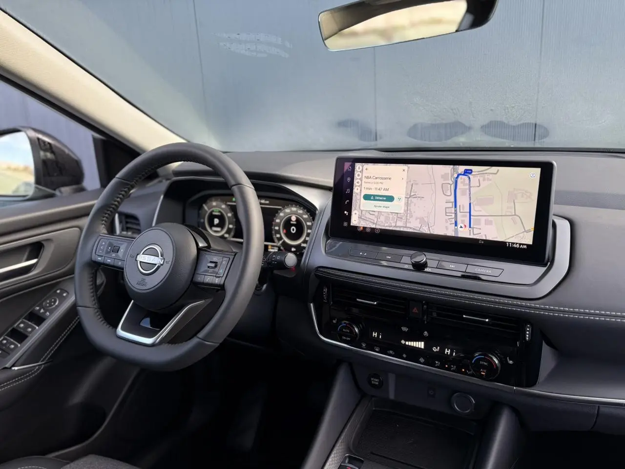 Vue intérieure côté conducteur du Nissan Qashqai blanc nacré 2025, tableau de bord avec écran tactile et volant cuir.