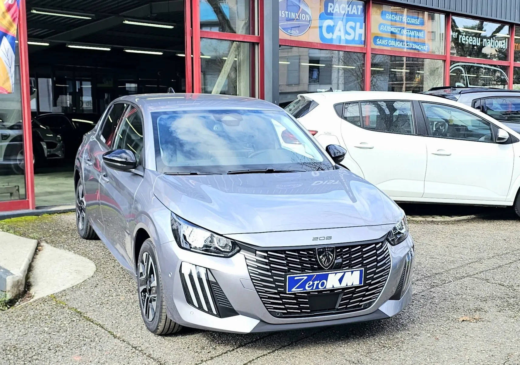 PEUGEOT 208 110 hybrid gris vue 3/4 avant droit, calandre noire distinctive et feux LED verticaux marquants.