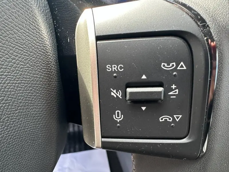 Gros plan sur les commandes audio au volant noir de la Citroën C3 1.2 Turbo 100ch MAX, avec boutons SRC et micro.
