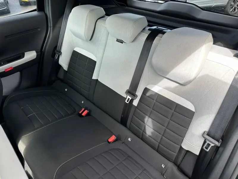 Vue intérieure de la banquette arrière bicolore noir et gris clair de la Citroën C3 2025, avec ceintures de sécurité visibles.