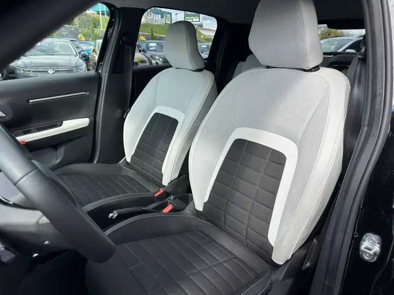 Vue intérieure des sièges avant bi-ton noir et clair de la Citroën C3 1.2 Turbo 100ch MAX, porte ouverte côté conducteur.