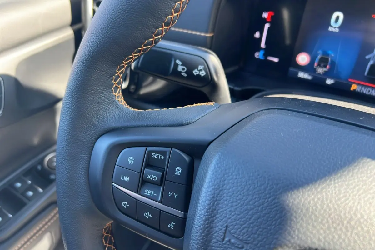 Gros plan sur le volant cuir noir avec surpiqûres marron et commandes multifonctions du Ford Ranger Wildtrak 2025.