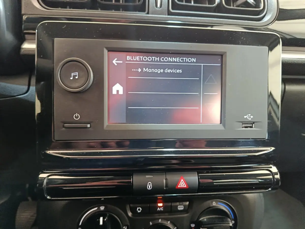 Gros plan sur l’écran tactile central et la console noire brillante du tableau de bord d’une Citroën C3 blanche de 2021.
