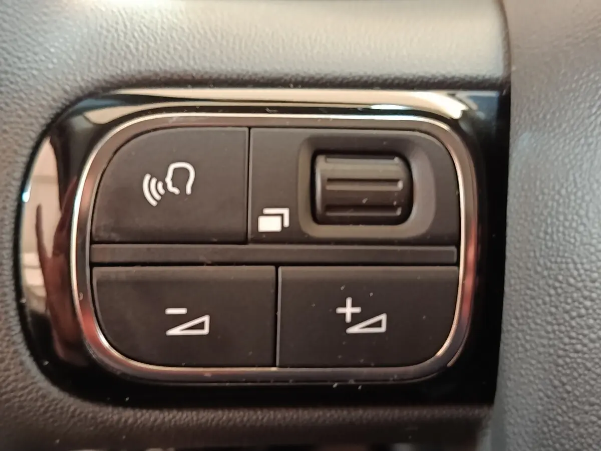 Gros plan sur les commandes noires du volant multifonctions de la Citroën C3 blanche, version BlueHDi 100 S&S BVM Feel.