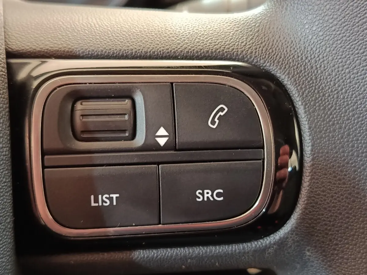Gros plan sur les commandes noires du volant multifonctions du Citroën C3 blanc, version BlueHDi 100 S&S BVM Feel.