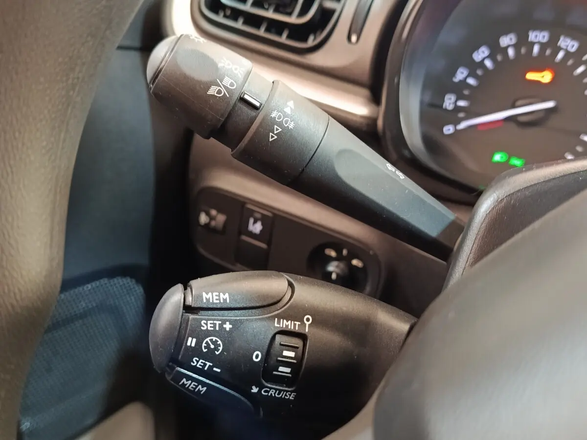 Gros plan sur les commandes de régulateur de vitesse et phares du tableau de bord d’une Citroën C3 blanche 2021.