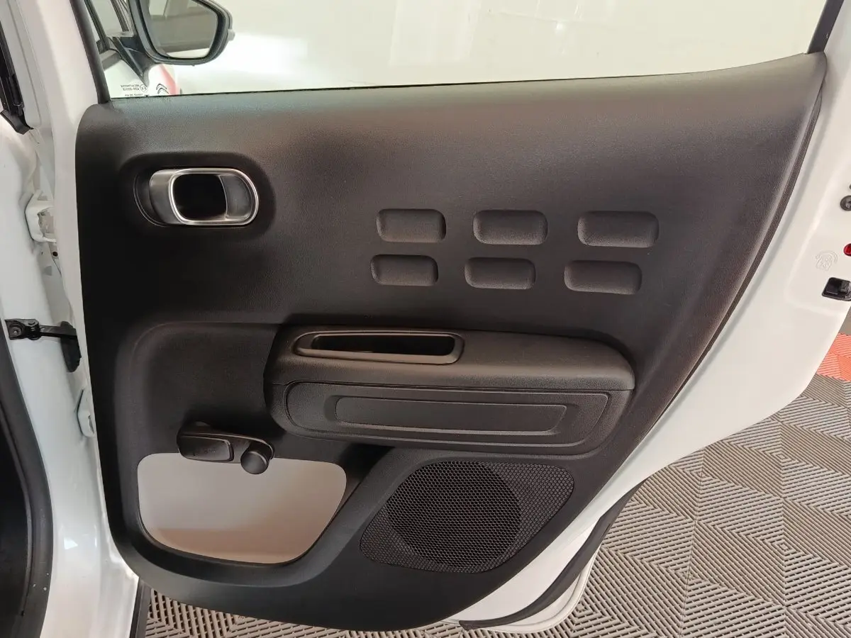 Vue intérieure de la porte arrière gauche blanche d'une Citroën C3 2021 avec poignée et haut-parleur intégrés.