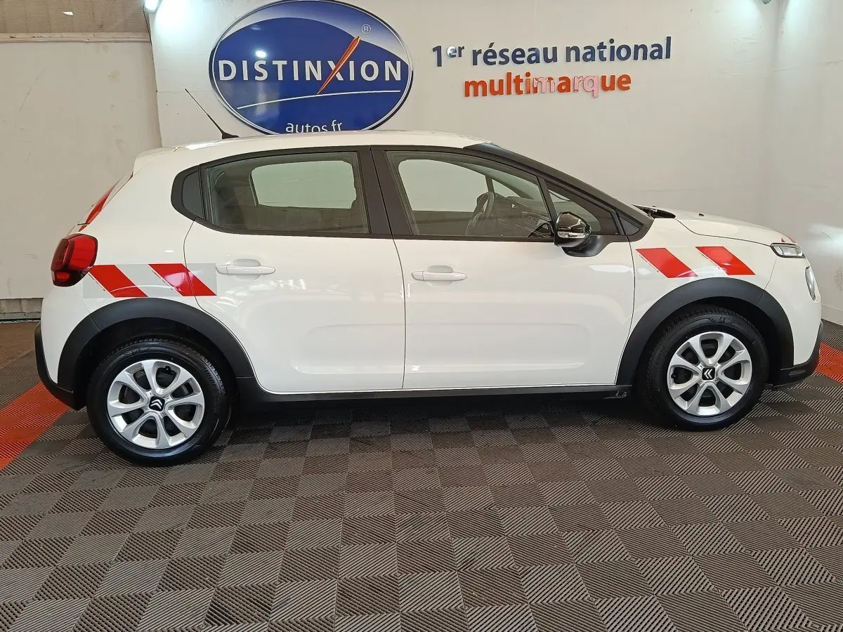 Profil côté gauche d'une Citroën C3 blanche 2021 avec bandes rouges diagonales sur ailes avant et arrière.
