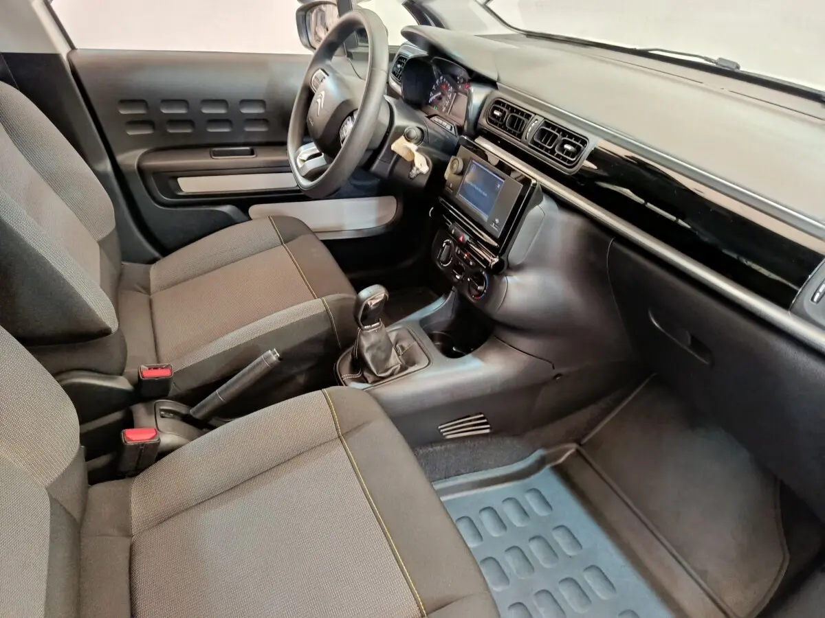 Vue intérieure côté conducteur de la Citroën C3 2021 avec tableau de bord noir et sièges tissu gris.