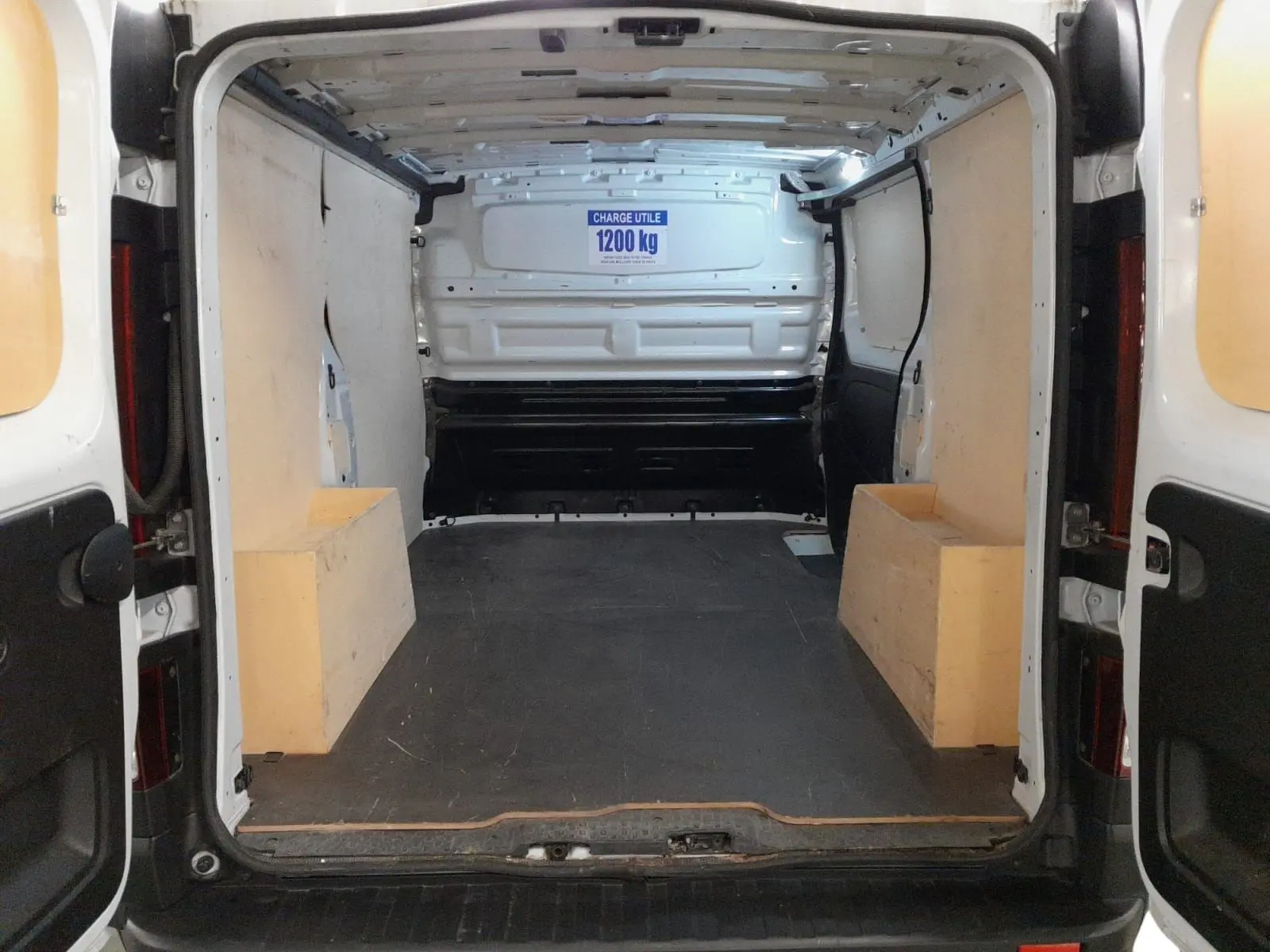 Vue intérieure arrière du Renault Trafic Fourgon blanc minéral 2024, montrant l’espace de chargement vide et ses protections latérales.