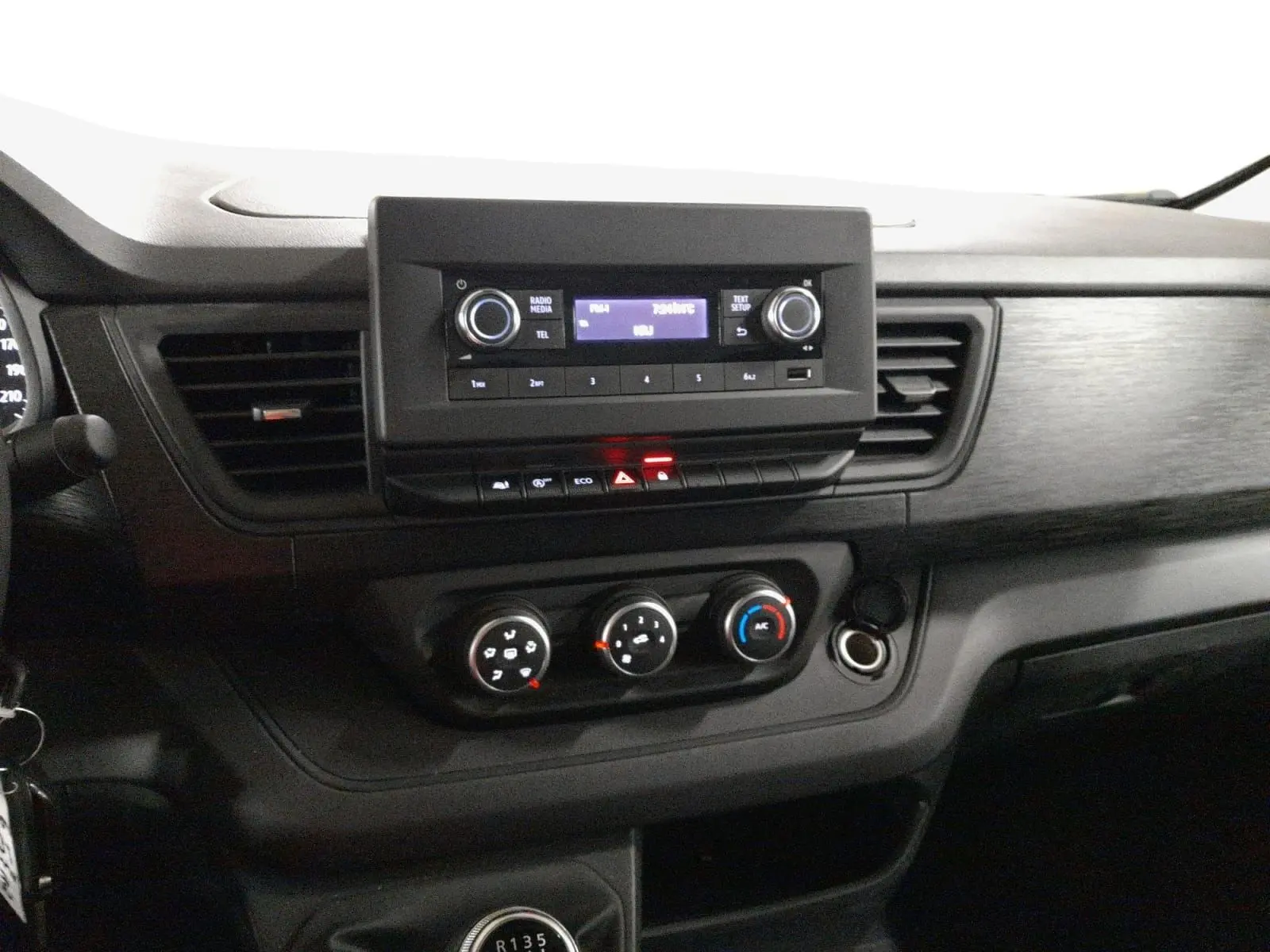 Tableau de bord du Renault Trafic Fourgon 2024, vue centrée sur la console avec radio, climatisation et levier de vitesses.