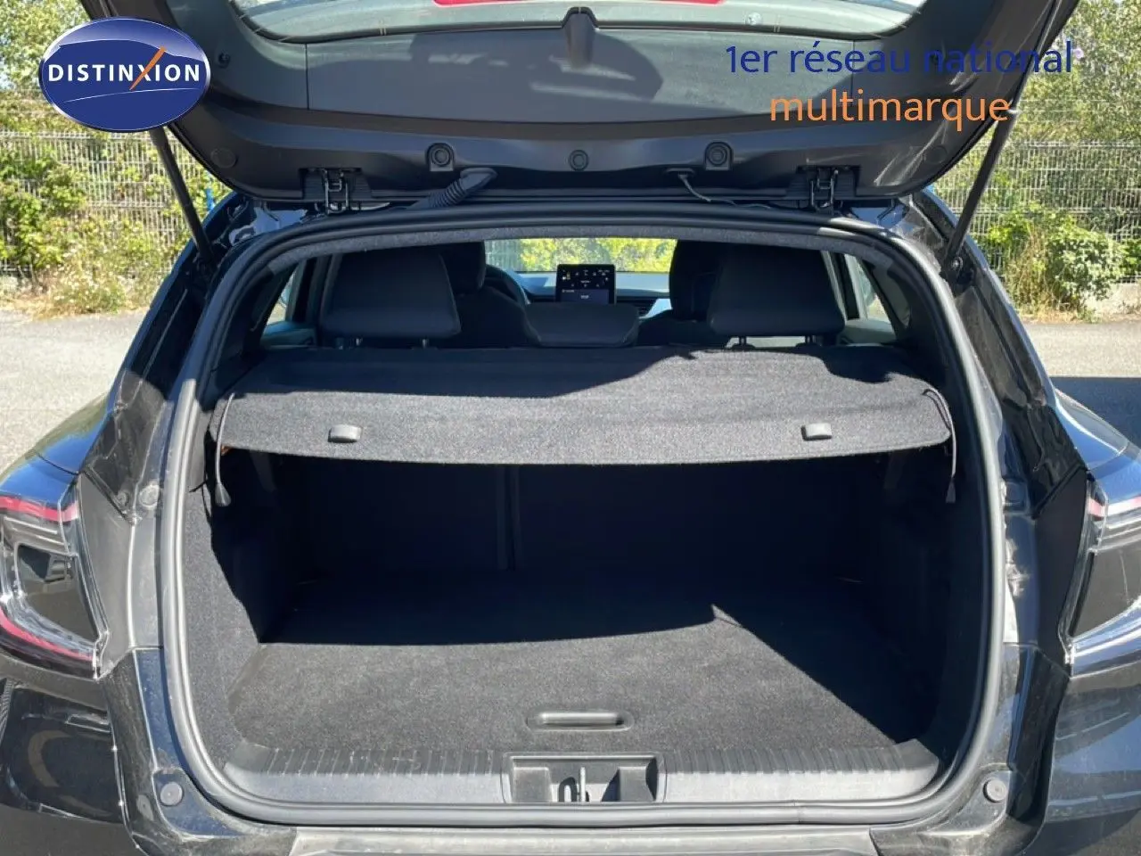 Coffre ouvert en vue arrière d’un Renault Captur noir étoile métal, montrant l’espace de chargement et la tablette arrière.