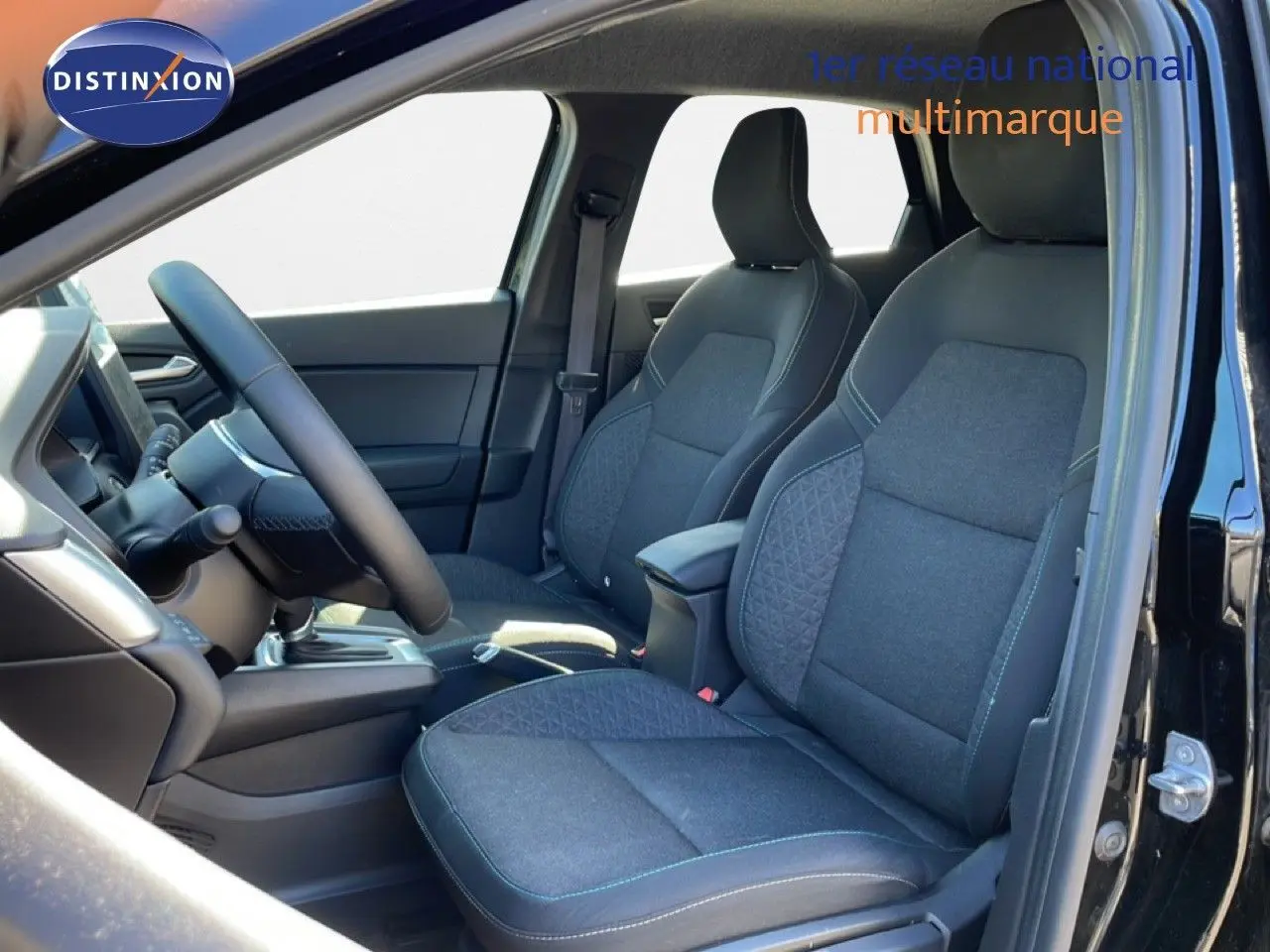 Vue intérieure côté conducteur du Renault Captur E-Tech Full Hybrid 2025, sièges tissu noir avec surpiqûres bleues.