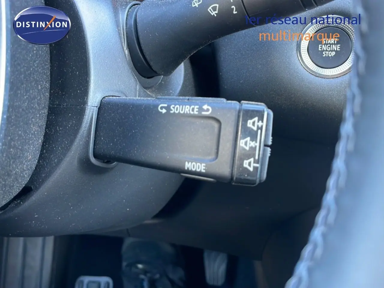 Gros plan sur la commande au volant du Renault Captur noir étoile métal, mettant en valeur le bouton source et mode.