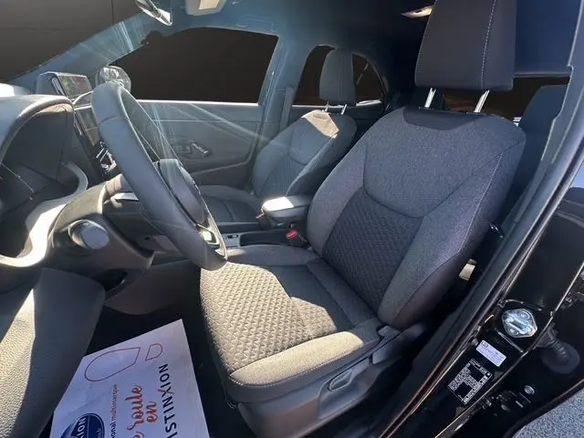 Intérieur de la Toyota Yaris Cross 130H Design 2025 en noir, vue côté conducteur montrant sièges tissu gris et tableau de bord.