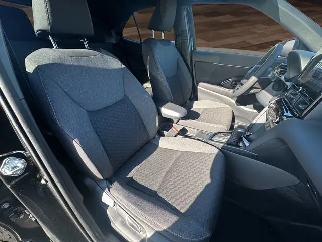 Vue intérieure des sièges avant gris du Toyota Yaris Cross 130H Design MY25 noir, avec console centrale et volant visibles.