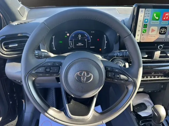 Vue rapprochée du volant noir de la Toyota Yaris Cross 130H Design 2025 avec tableau de bord numérique et écran tactile.