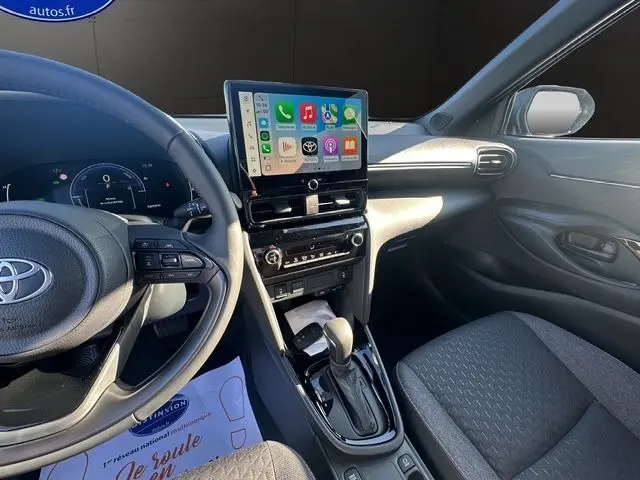 Vue intérieure côté conducteur du Toyota Yaris Cross 130H Design 2025, avec écran tactile central et volant multifonction noir.