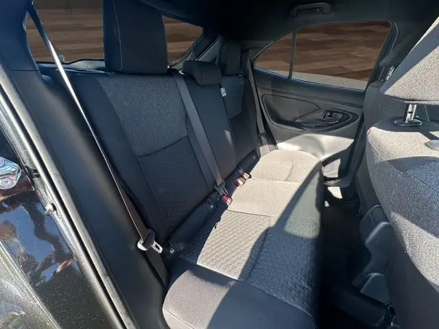 Vue intérieure arrière côté droit montrant la banquette noire du Toyota Yaris Cross 130H Design 2025 en essence hybride.