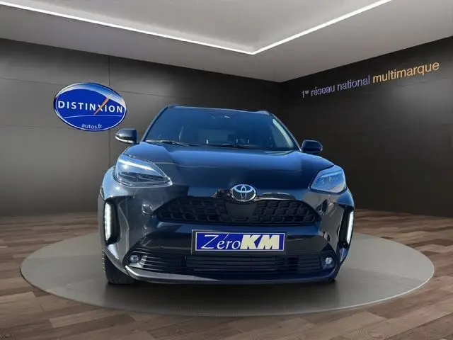 Vue frontale d'une Toyota Yaris Cross 130H Design 2025 noire, exposée en showroom avec plaque Zero KM.