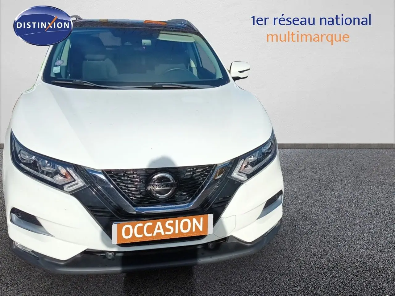 Vue avant d'un Nissan Qashqai blanc de 2018 avec calandre noire et plaques "OCCASION" en orange.