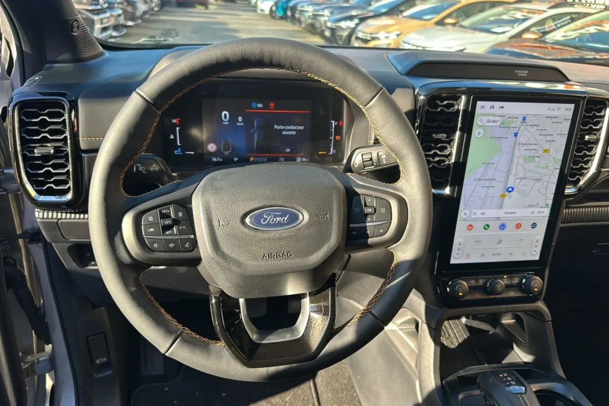 Vue intérieure centrée sur le volant cuir multifonctions Ford Ranger 2025 avec écran tactile GPS vertical.