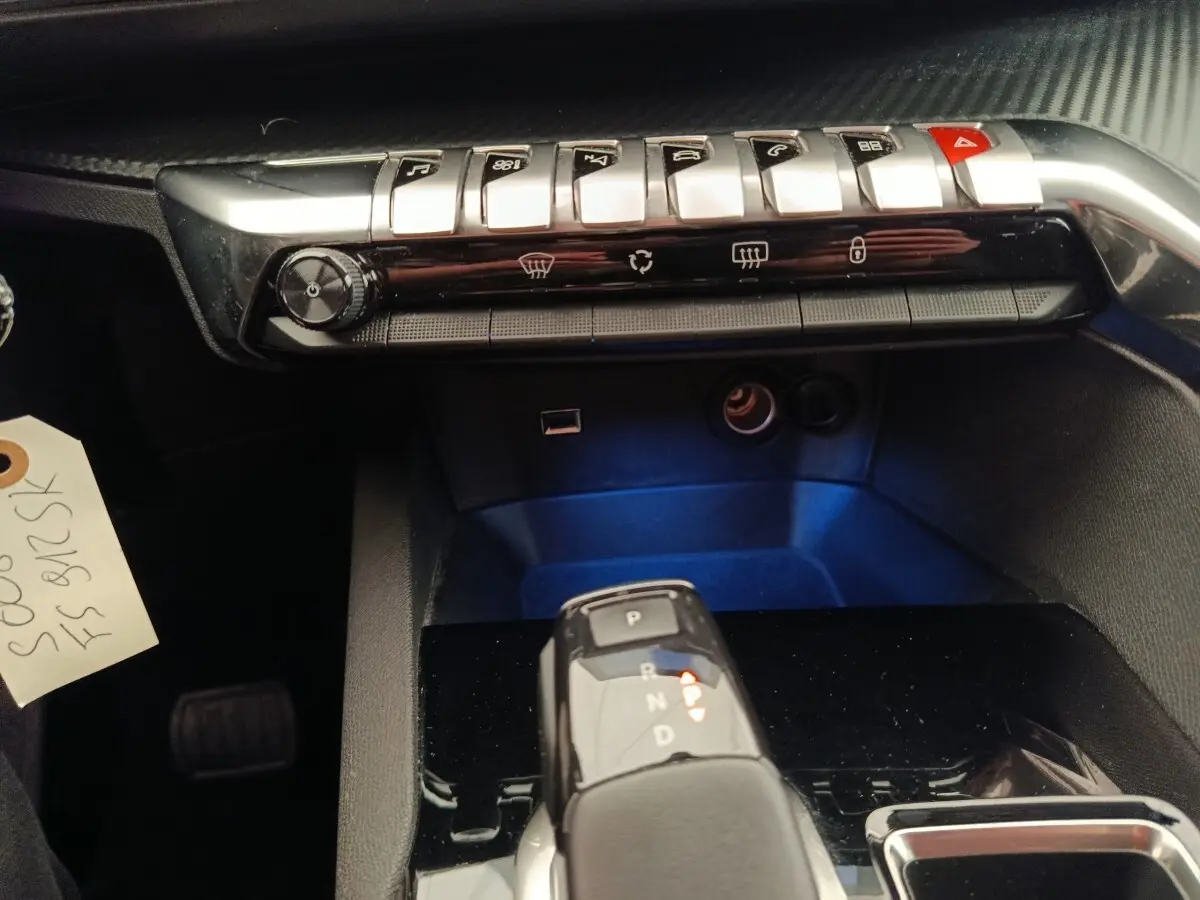 Gros plan sur la console centrale du Peugeot 5008 gris foncé, avec levier de vitesse automatique et commandes piano.
