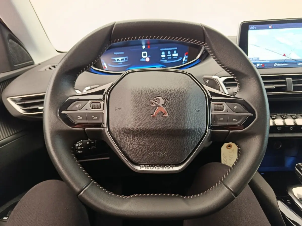 Vue intérieure centrée sur le volant cuir noir du Peugeot 5008 2020 avec tableau de bord digital et écran tactile.