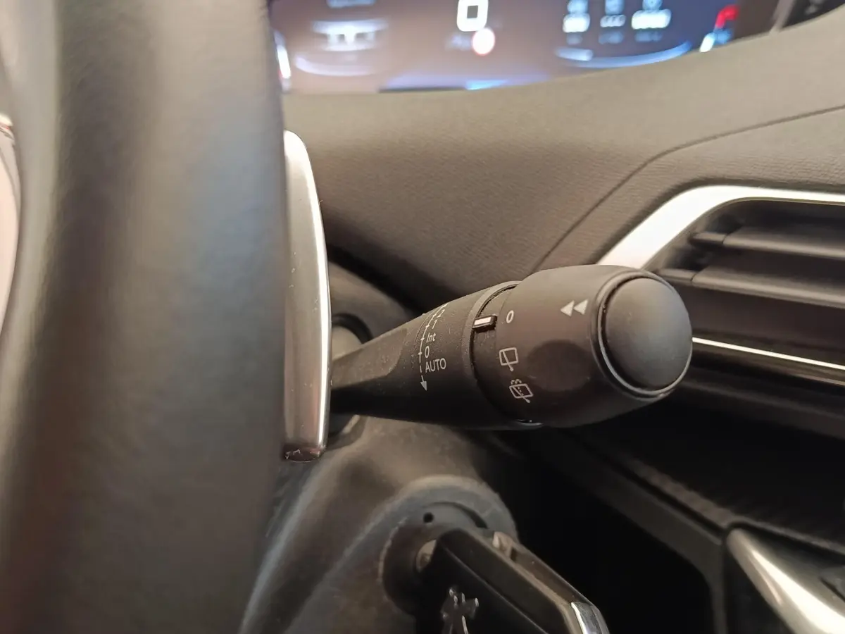 Gros plan sur la commande d’essuie-glace côté gauche du volant dans l’habitacle du Peugeot 5008 gris foncé.