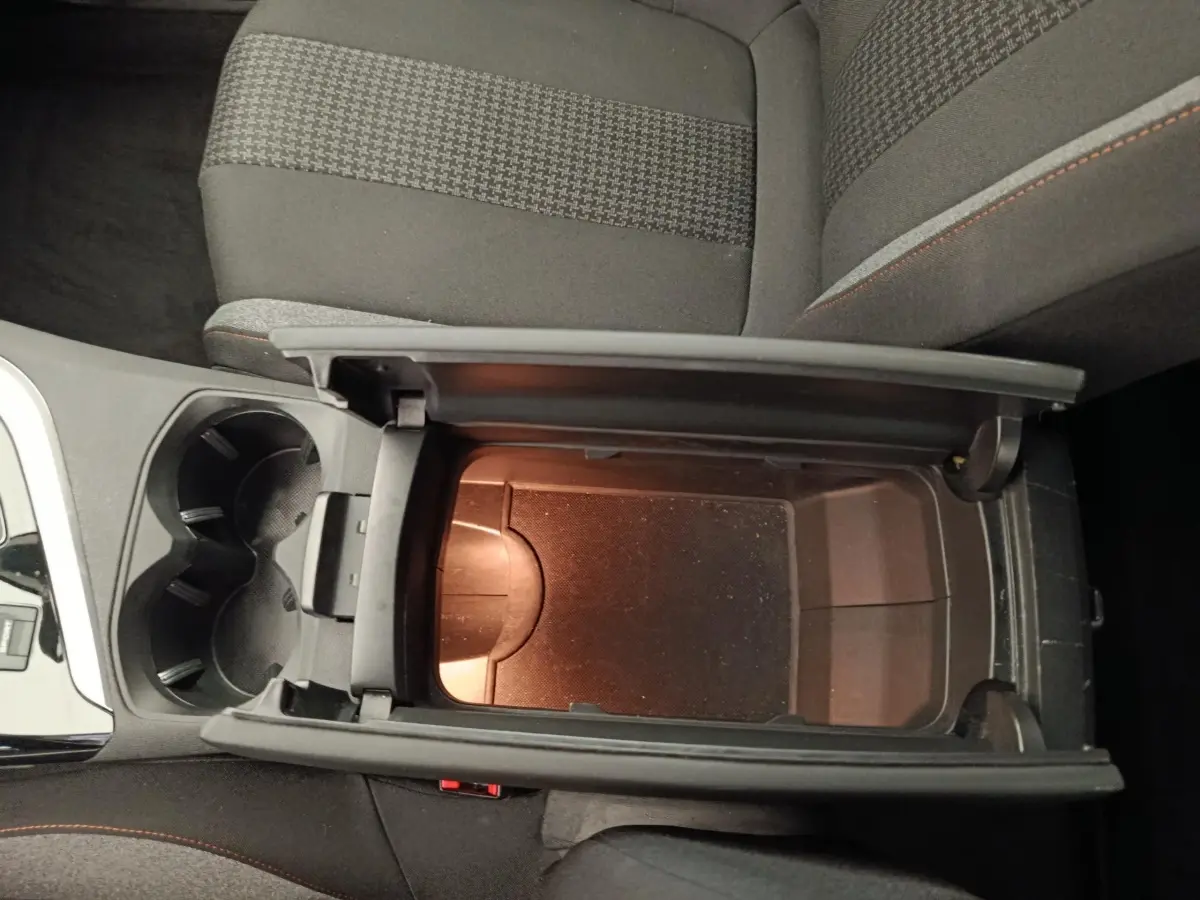 Vue plongeante sur la console centrale ouverte du Peugeot 5008 gris foncé, montrant le rangement intérieur et porte-gobelets.