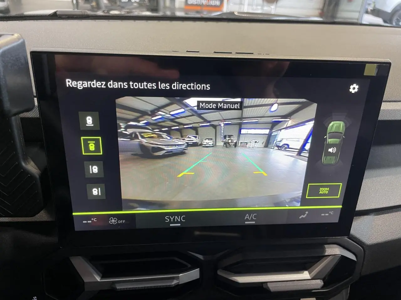 Écran tactile intérieur montrant la caméra de recul d'un Dacia Bigster gris schiste dans un garage.