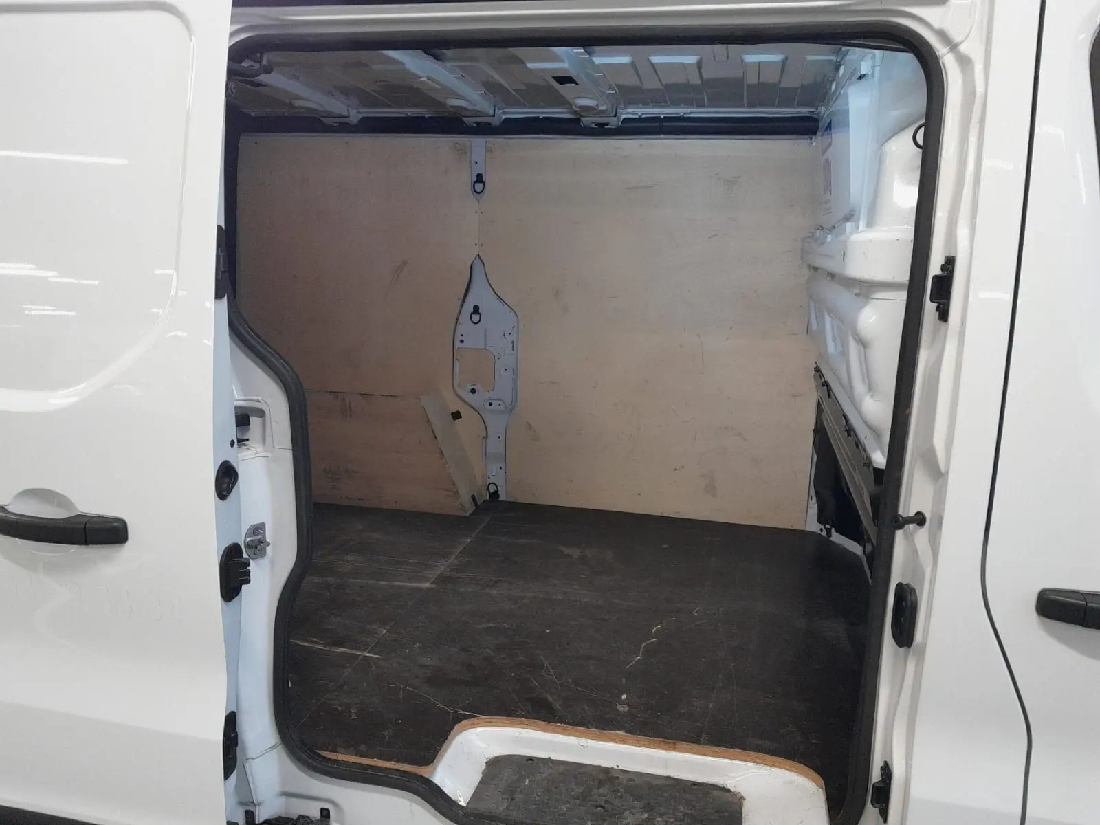 Vue intérieure de la partie chargement du Renault Trafic Fourgon blanc minéral, porte latérale droite ouverte.