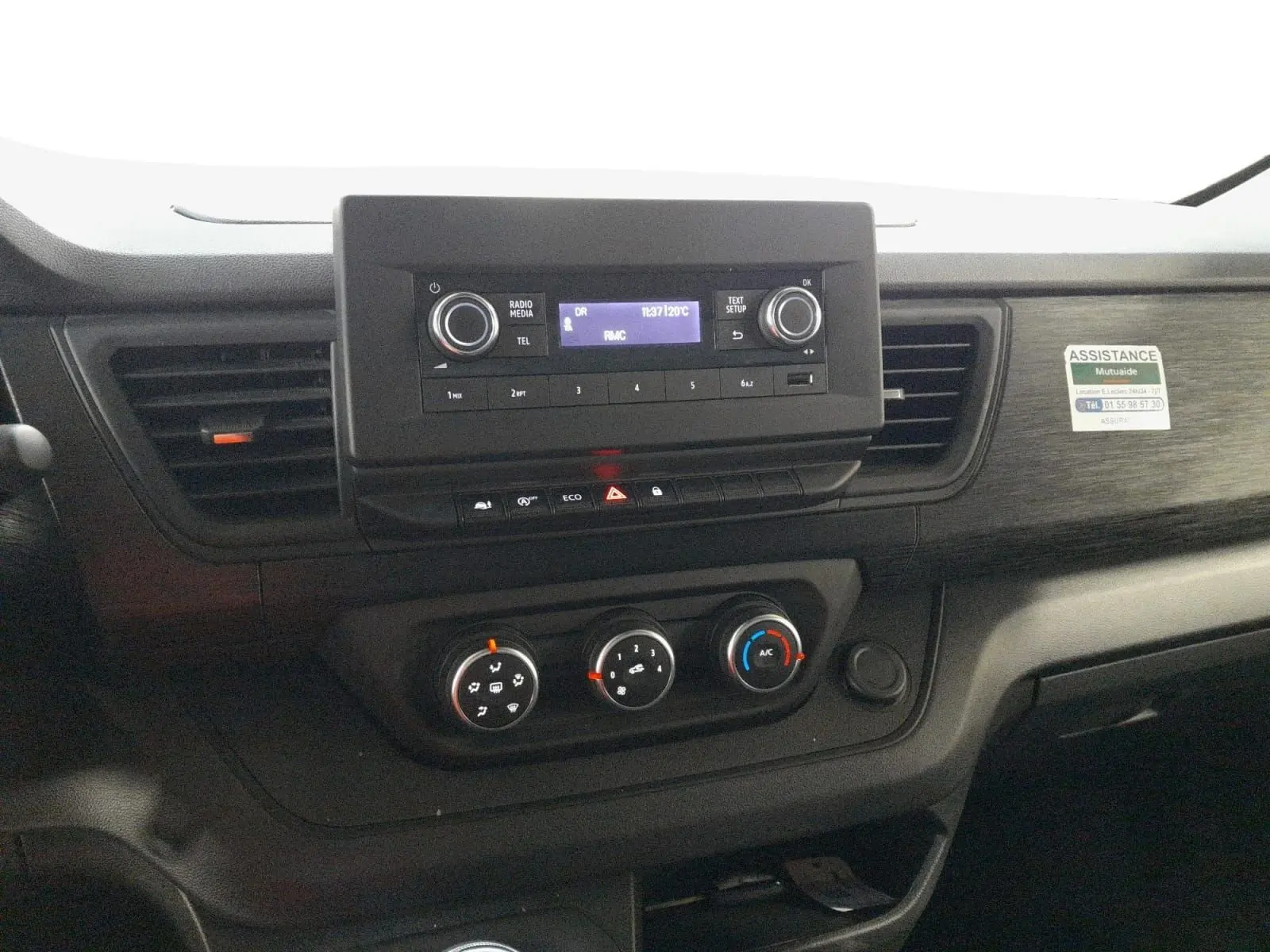 Vue rapprochée du tableau de bord noir du Renault Trafic Fourgon 2024 avec commandes climatisation et radio intégrée.