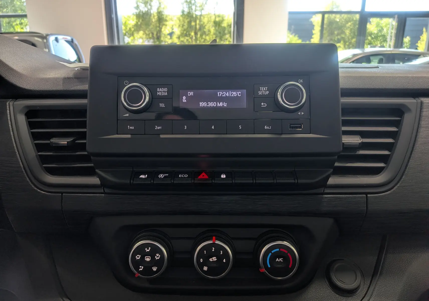 Tableau de bord du Renault Trafic Fourgon 2024 avec système radio central et commandes de climatisation en vue frontale.