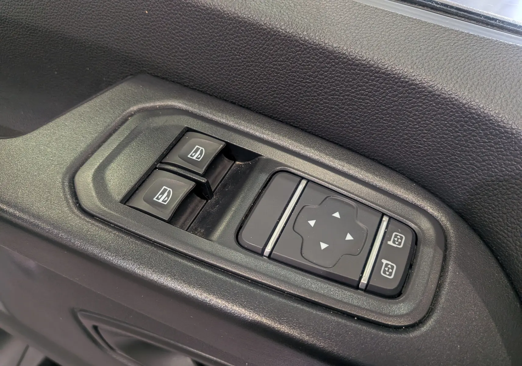 Gros plan sur les commandes de lève-vitres et réglage des rétroviseurs côté conducteur du Renault Trafic Fourgon blanc 2024.