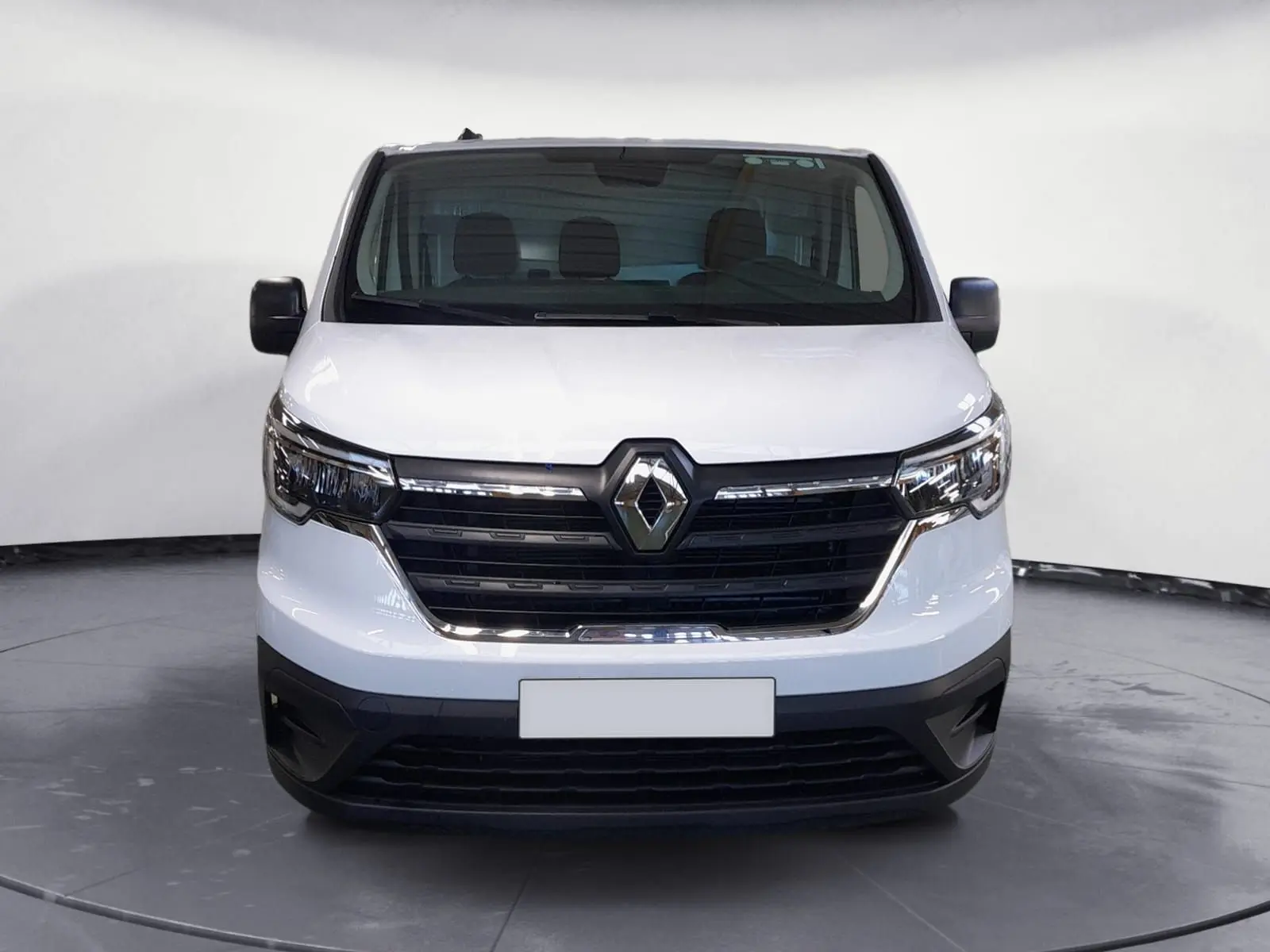 Vue frontale d’un Renault Trafic Fourgon blanc minéral 2024 avec calandre noire et logo Renault central bien visible.